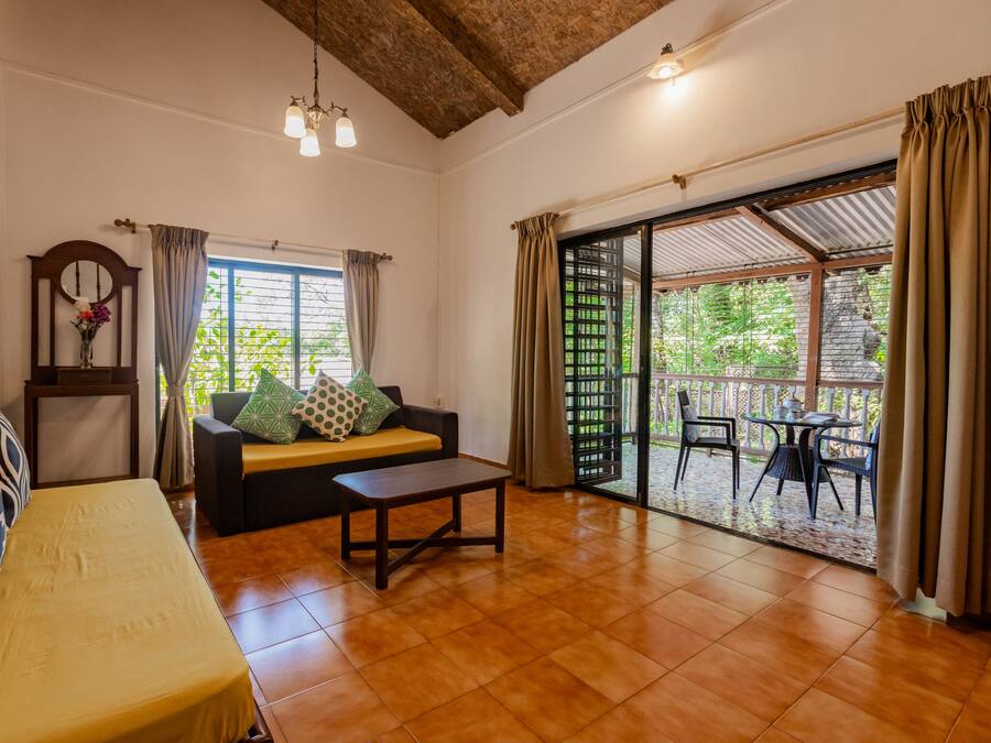 A spacious living area with a sofa, a small table, and a view through a glass door to an outdoor patio.