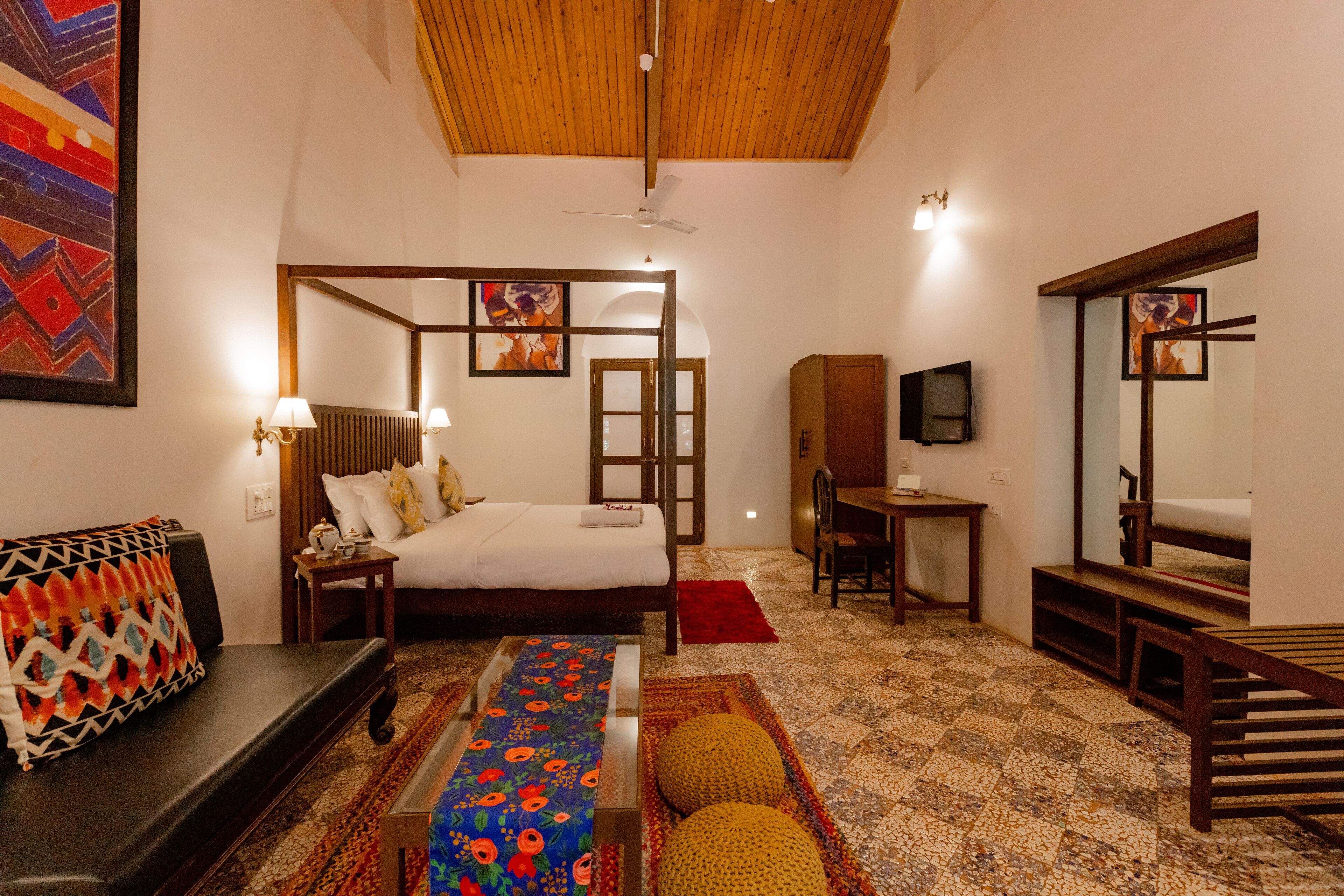 A bedroom with a bed, bedside table, lamp, and a wooden bench.