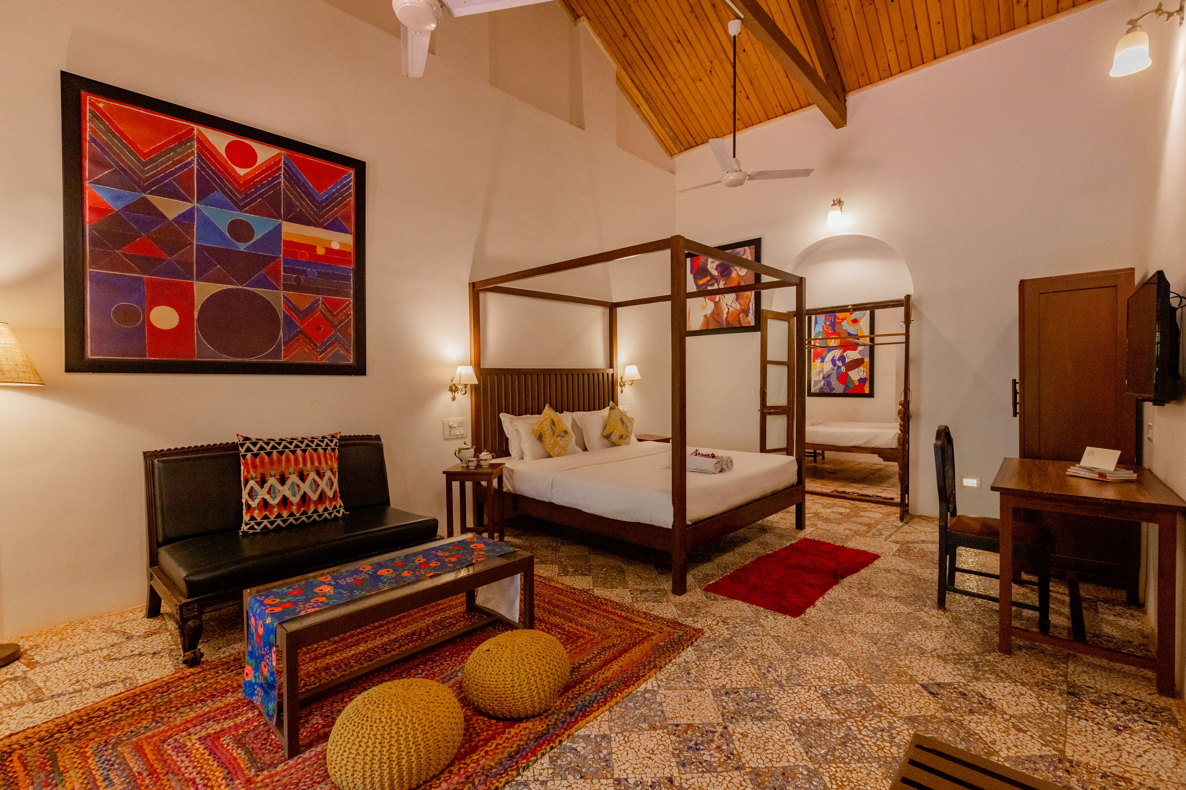 A bedroom with a four-poster bed, a sofa, a desk, and a chair.