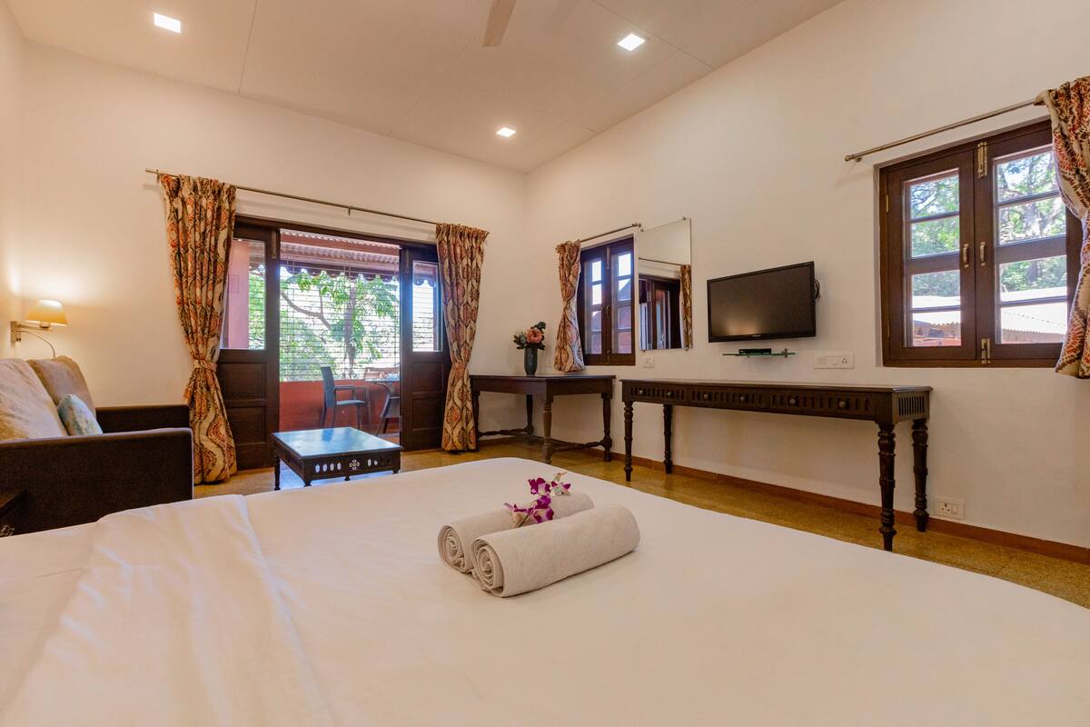 Una habitación de hotel con cama, escritorio, televisor y cortinas.