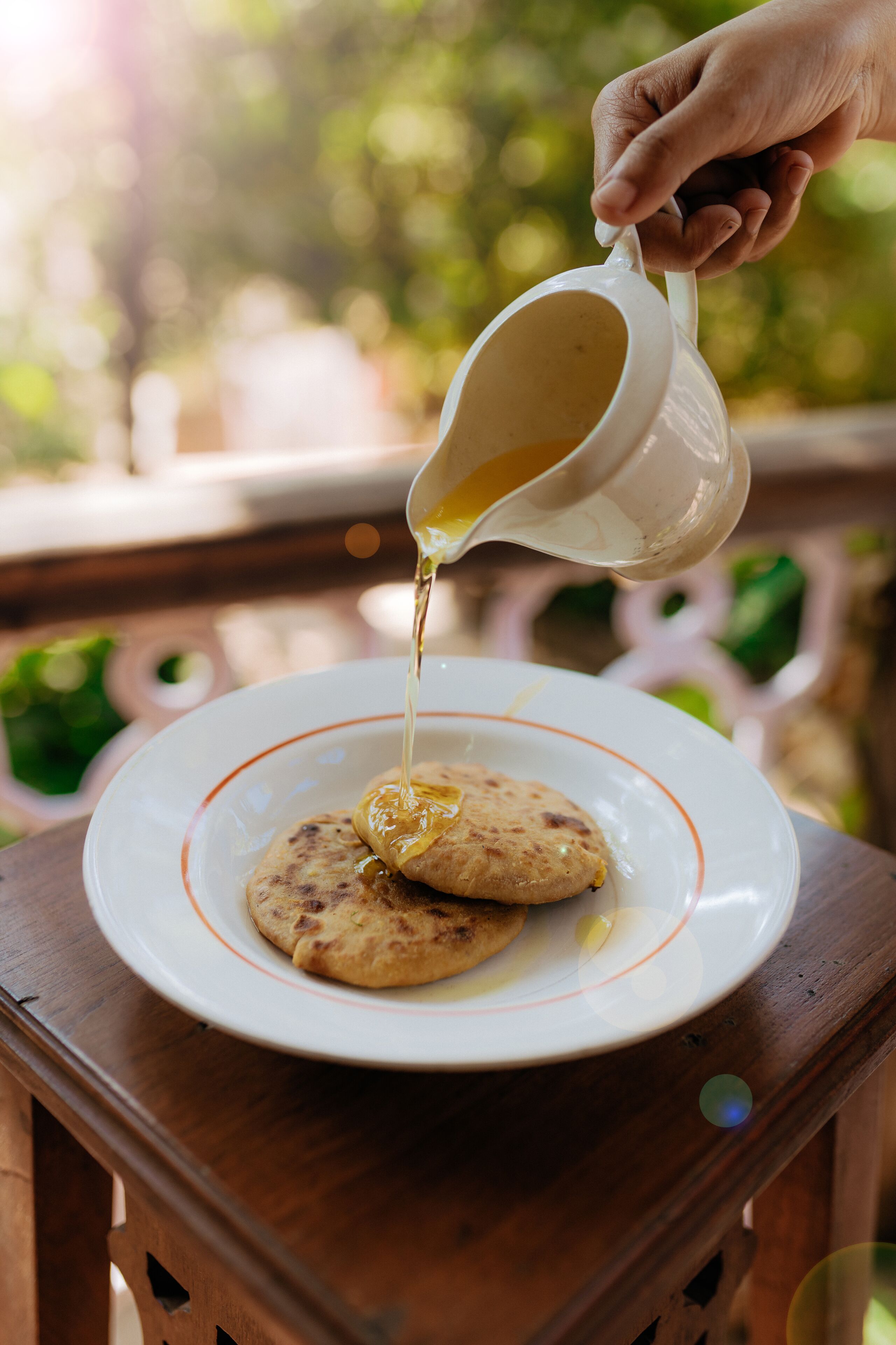 A hand pouring syrup over a plate of flatbreads.