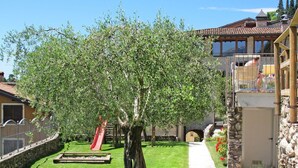 A residential area with a large tree, a pathway, and a small playground.
