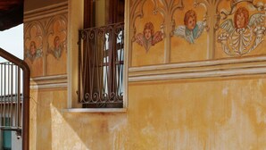 Une façade d’immeuble ornée d’une fenêtre et de motifs décoratifs muraux représentant des figures angéliques.