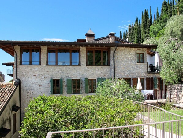 Un bâtiment en pierre doté de nombreuses fenêtres et d’un balcon.
