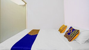 Un lit bien fait, recouvert d’une couvre-lit bleue et jaune, et agrémenté de deux coussins décoratifs.