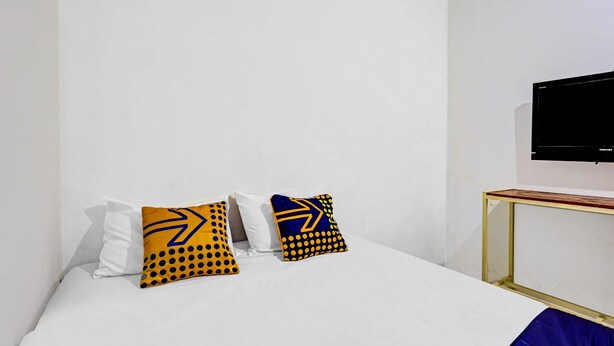 Une chambre d’hôtel avec un lit, deux oreillers, un téléviseur fixé au mur et une petite table.