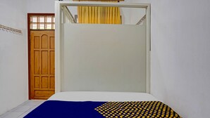 Une pièce avec un lit, une porte en bois et un rideau.