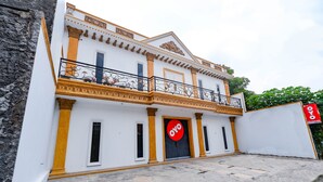 A two-story building with a balcony, a large door with a sign, and a stone-paved entrance. - OYO 2856 Wisma Fortuna Syariah (Surakarta)