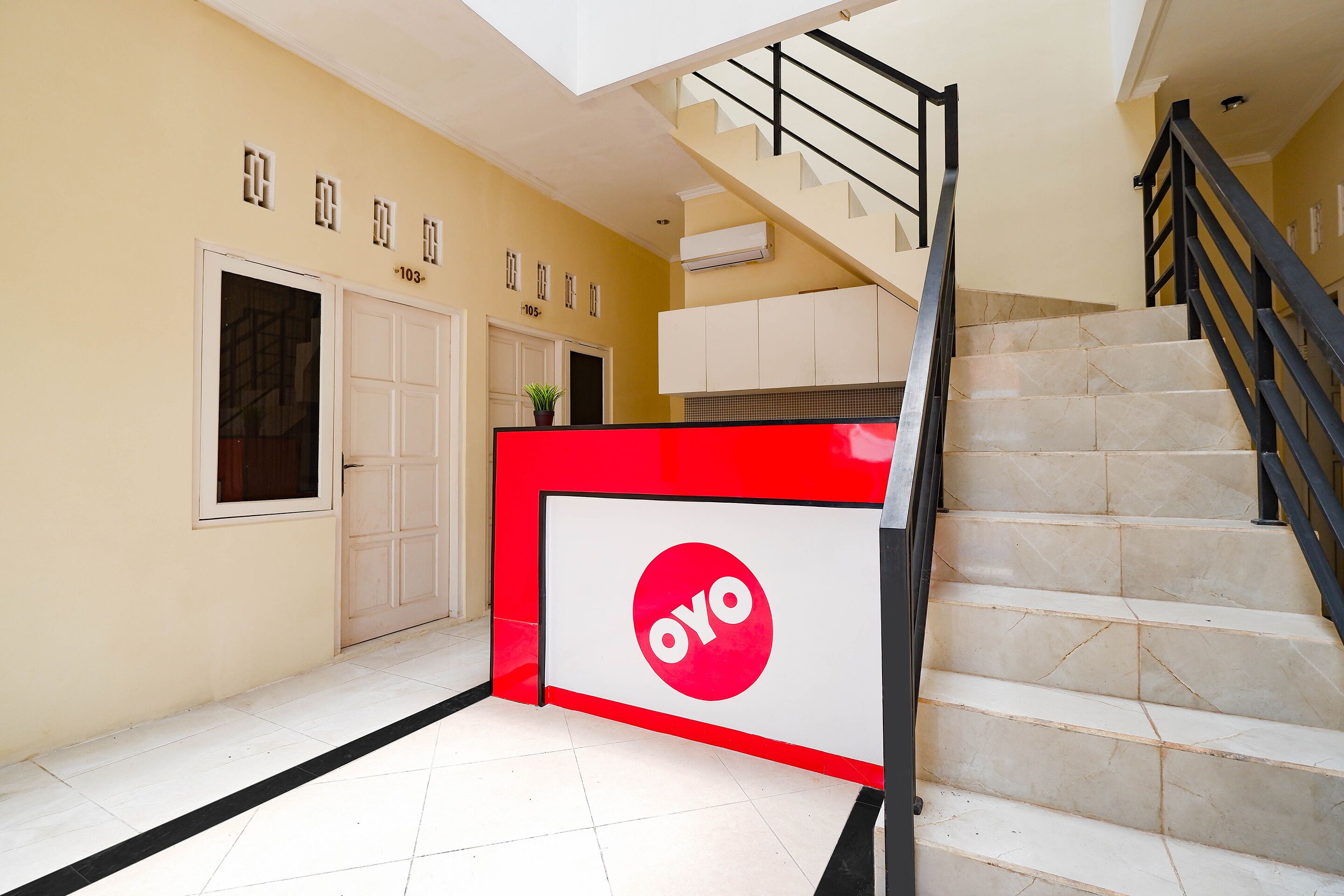 A staircase with a red and white sign, a white door, and a plant on the wall.