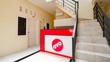 A staircase with a red and white sign, a white door, and a plant on the wall.