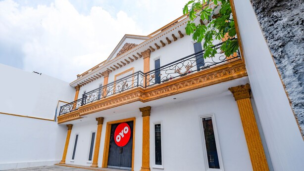 A building with a white facade, a balcony with ornate railings, and a large circular sign with the word "OYO". - OYO 2856 Wisma Fortuna Syariah (Surakarta)
