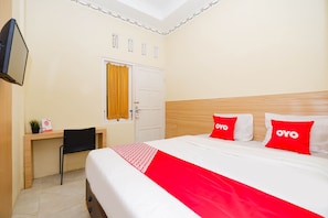 Habitació d'hotel amb llit, escriptori, cadira, televisió i porta amb cortina.