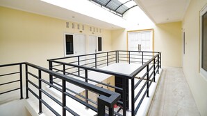 A spacious balcony with a glass ceiling, white walls, and a black railing. - OYO 2856 Wisma Fortuna Syariah (Surakarta)