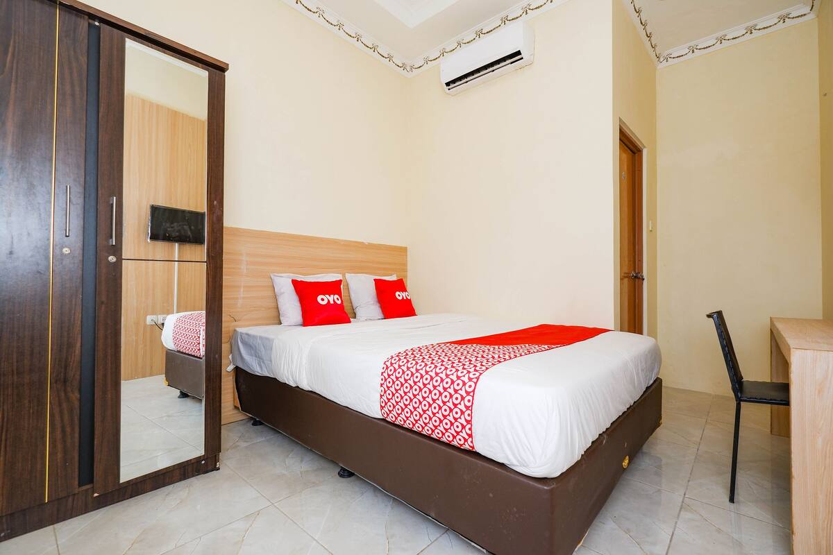 A bedroom with a bed, a desk, and a chair.