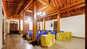 A spacious hall with wooden beams, blue chairs, and yellow-covered tables, likely set up for an event. - OYO 2634 Griya Birowo Syariah (Wonosari)