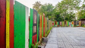 A row of colorful, weathered wooden doors with a paved walkway in front. - OYO 2634 Griya Birowo Syariah (Wonosari)