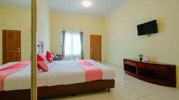 A hotel room with a large bed, a TV mounted on the wall, and a wooden cabinet.
