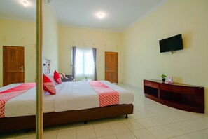 A hotel room with a large bed, a TV mounted on the wall, and a wooden cabinet. - OYO 2634 Griya Birowo Syariah (Wonosari)