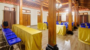 A spacious hall with wooden beams, tables covered with yellow tablecloths, and blue chairs arranged for an event. - OYO 2634 Griya Birowo Syariah (Wonosari)