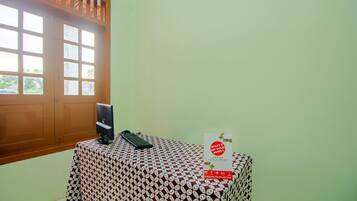 A room with a table covered by a patterned tablecloth, a keyboard, a telephone, and a sign with text.