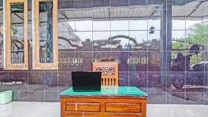 A wooden table with a laptop on top, a green cushion, and a decorative chair. - OYO Life 2546 Griya Widya Syariah (Klaten)