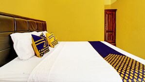 A hotel room with a bed, a wooden door, and yellow walls. - OYO Life 2546 Griya Widya Syariah (Klaten)