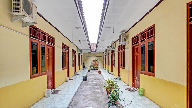 A corridor with tiled floors, potted plants, and air conditioning units on the walls. - OYO Life 2546 Griya Widya Syariah (Klaten)
