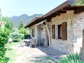 Un bâtiment en pierre doté d’un patio couvert, d’un espace extérieur aménagé pour s’asseoir et surplombant un paysage montagneux.