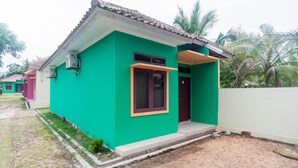 A single-story house with a green exterior, a tiled roof, and a small porch. - OYO 2471 Swarna Raya (Bayah)