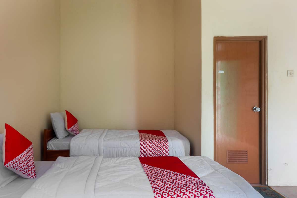 Una camera d'albergo con due letti, ciascuno con una coperta a righe rosse e bianche, e una porta in legno.