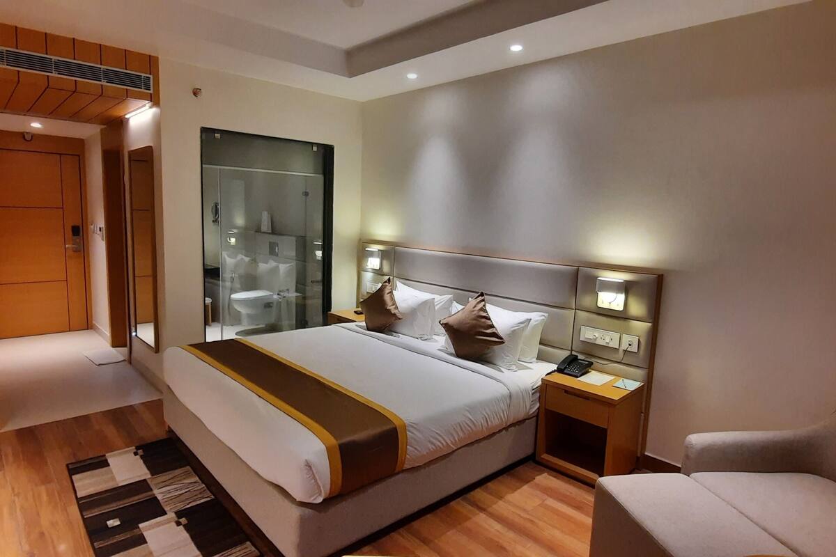 A modern hotel room with a large bed, bedside tables, a chair, and a walk-in closet.