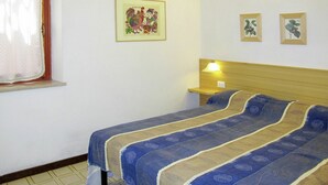 A bedroom with a bed, a nightstand, a lamp, and a window with curtains.