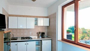 A compact kitchen with white cabinets, a gas stove, and a coffee maker. - Lovely apartment for 5 people with WIFI, A/C, pool, TV and terrace (Torri Del Benaco)