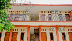 Un edificio de dos pisos con una escalera central, varias puertas y unidades de aire acondicionado.