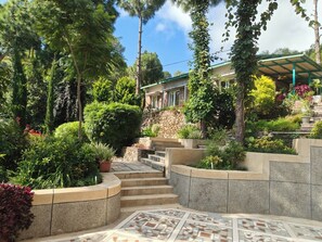 A garden with stone steps leading to a building with a green roof.