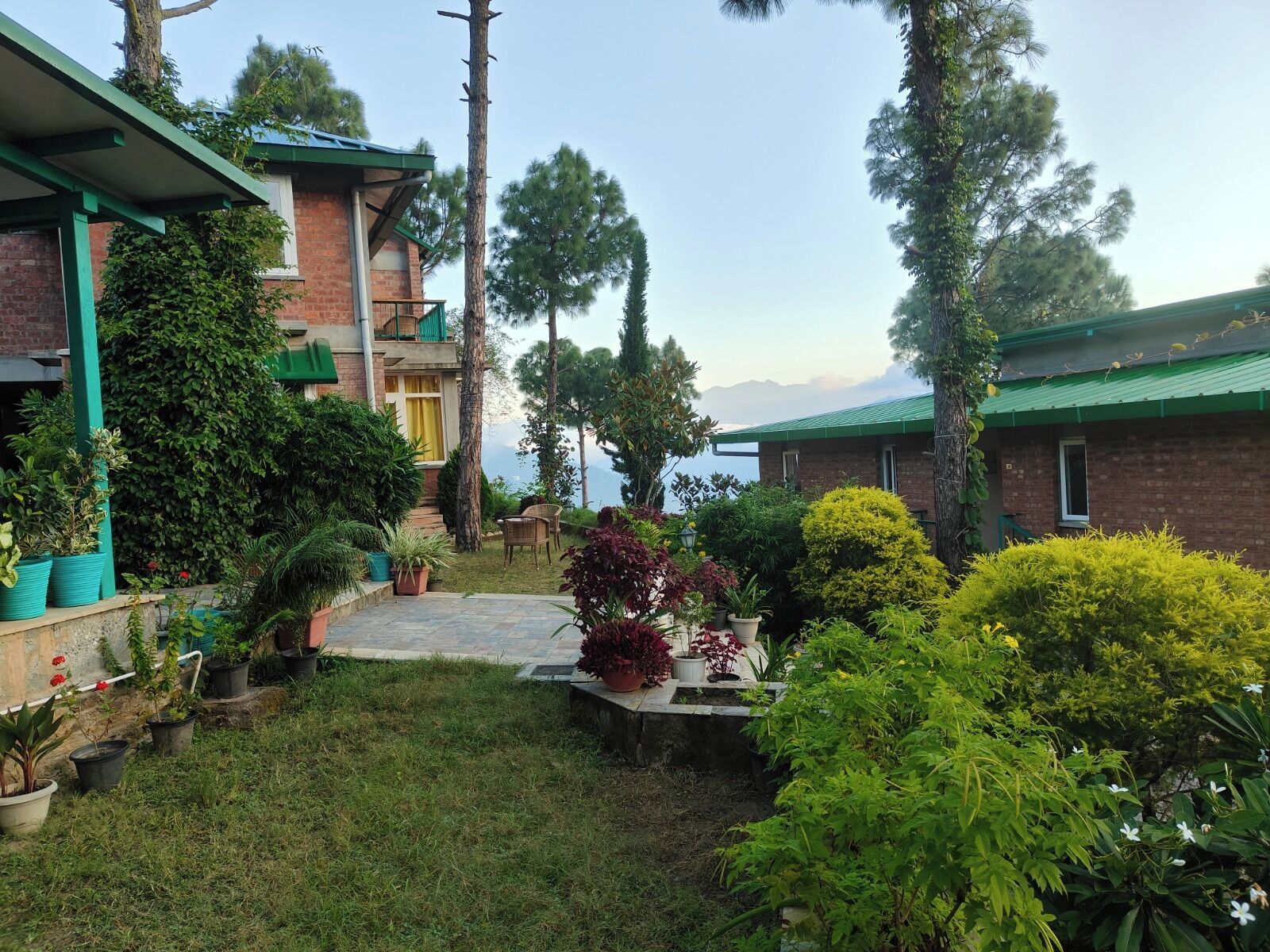 A courtyard with a brick building, potted plants, and a view of the mountains.