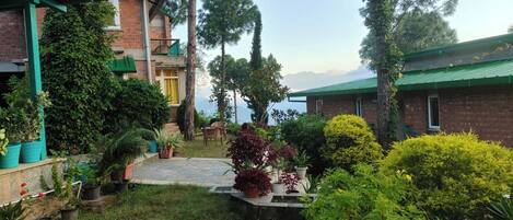 A courtyard with a brick building, potted plants, and a view of the mountains.