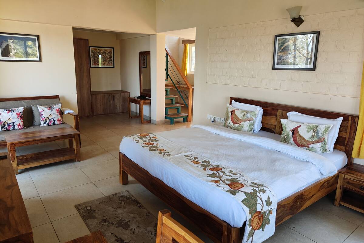 A spacious bedroom with a large bed, wooden furniture, and a staircase leading to another room.