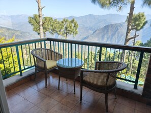 A balcony with wicker furniture and a view of mountains.