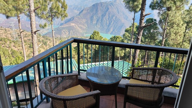 A balcony with wicker furniture and a view of mountains. - Azalea (Narendranagar)