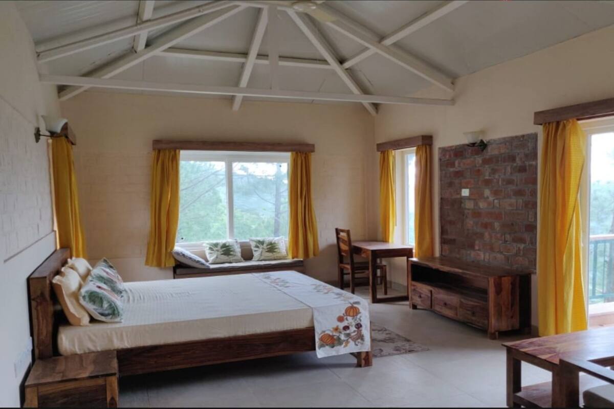 A bedroom with a bed, a wooden table, a TV, and a brick wall.