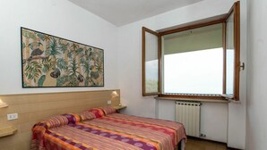 Un dormitorio con una cama, una ventana, un radiador y un cuadro en la pared.