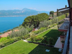 Uma varanda com vista para um jardim bem cuidado e paisagem costeira.