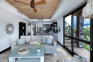 Una sala de estar moderna con un sofá, una mesa de centro y vistas a la cocina y el área exterior.