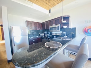 Una cocina moderna con armarios de madera oscura, electrodomésticos de acero inoxidable y una encimera de granito negro.