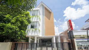 A modern building with a white facade, a wooden section, and a gated entrance.