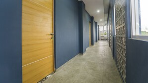 A corridor with blue walls, a wooden door, and a patterned floor.