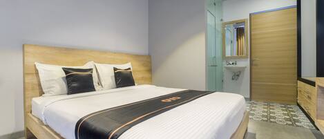 Una habitación de hotel con una cama de madera, un baño con espejo y lavabo, y un armario.