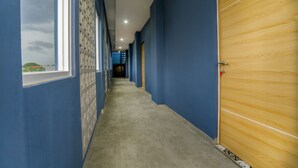 A hallway with blue walls, a wooden door, and a window with a view of a building.