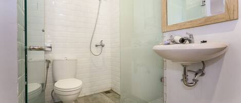 A modern bathroom with a glass-enclosed shower, a white toilet, and a sink with a wooden-framed mirror.